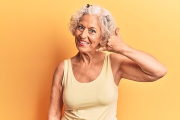 Wall Mural - Senior grey-haired woman wearing casual clothes smiling doing phone gesture with hand and fingers like talking on the telephone. communicating concepts.