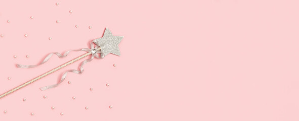 Festive decoration, magic wand, bright silver star with shine on soft pink background with copy space. Minimal holiday concept. Banner for website.