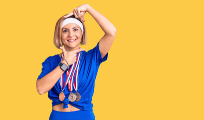 Poster - Young blonde woman wearing winner medals smiling making frame with hands and fingers with happy face. creativity and photography concept.