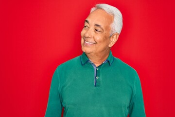 Sticker - Middle age senior grey-haired man wearing casual sweater over red isoalted background looking away to side with smile on face, natural expression. Laughing confident.