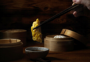 Wall Mural - Female with chopstick ready to eat steamed dumplings serving on bamboo seamer. Chinese traditional food