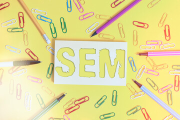 Wall Mural - Conceptual hand writing showing Sem. Concept meaning search engine marketing Internet marketing involves promotion of website Flat lay above empty paper with pencils and paper clips