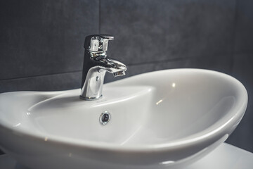 Faucet and water drop close up. Bathroom interior with sink and water tap.