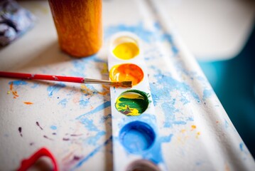 Sticker - Closeup shot of a small watercolor palette and a brush on a painting table for children