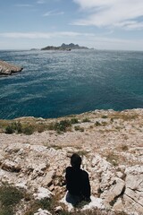 Canvas Print - Vertical view of the sea with a person standing on a rocky shore in Marseille, France