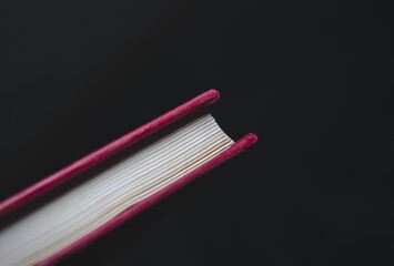 Poster - Closeup of a book with a red hardcover under the lights isolated on a dark background