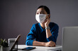 © chajamp - Asian woman wearing protective face mask working on a laptop at office. WFH. Work from home. Prevention Coronavirus COVID-19 concept.
