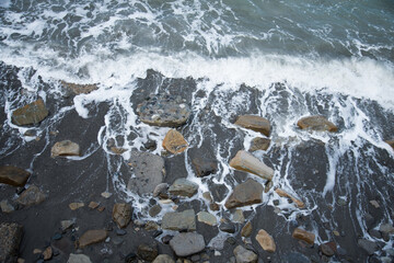 Top view of the sea wave and rocks. The water forms a whimsical pattern. Background, texture.