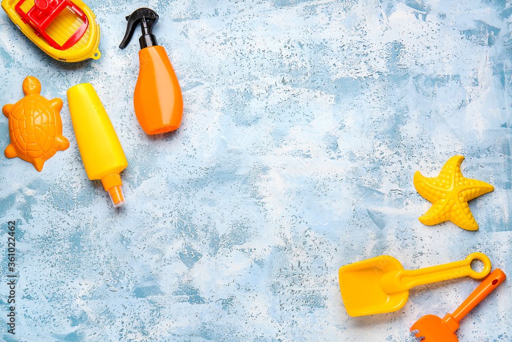Sunscreen cream with beach sand toys on color background