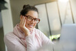 © goodluz - Smiling dark-haired woman with eyeglasses working on laptop