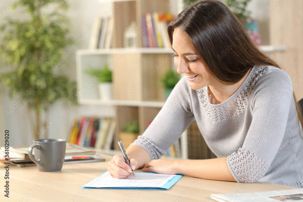 Happy Fill Form Happy woman filling out form on a desk at home Stock Photo | Adobe Stock