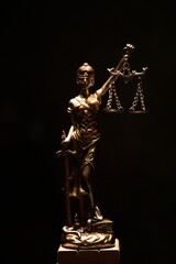 Sticker - Vertical shot of lady justice bronze statue isolated on a black background