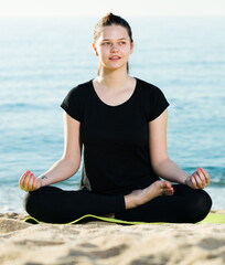 Wall Mural - Female 20-30 years old is sitting and doing meditation in black T-shirt