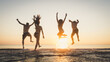 © Davide Angelini - Group of happy friends running and jumping in the sea at sunset. Young people enjoy holiday vacation at the beach.