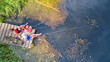 © Iuliia Sokolovska - Happy family and friends fishing together outdoors near lake in summer, aerial top view from above