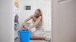 Woman wiping wet floor near leaking washing machine