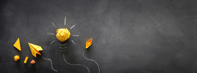 Wall Mural - Education concept image. Creative idea and innovation. Crumpled paper as light bulb metaphor over blackboard