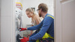 Woman Looking At Male Worker Checking Defects In Washing Machine