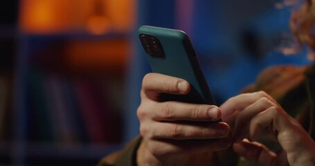 Close up view of males hands scrolling and touching screen while holding smartphone. Young guy using phone for browsing net. Concept of communication and leisure.Home background.