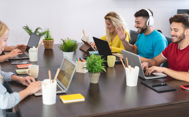 Young trendy teamwork using computer in creative coworking office - Business people working together at new startup project - Focus on man face with blue t-shirt - Technology and marketing concept