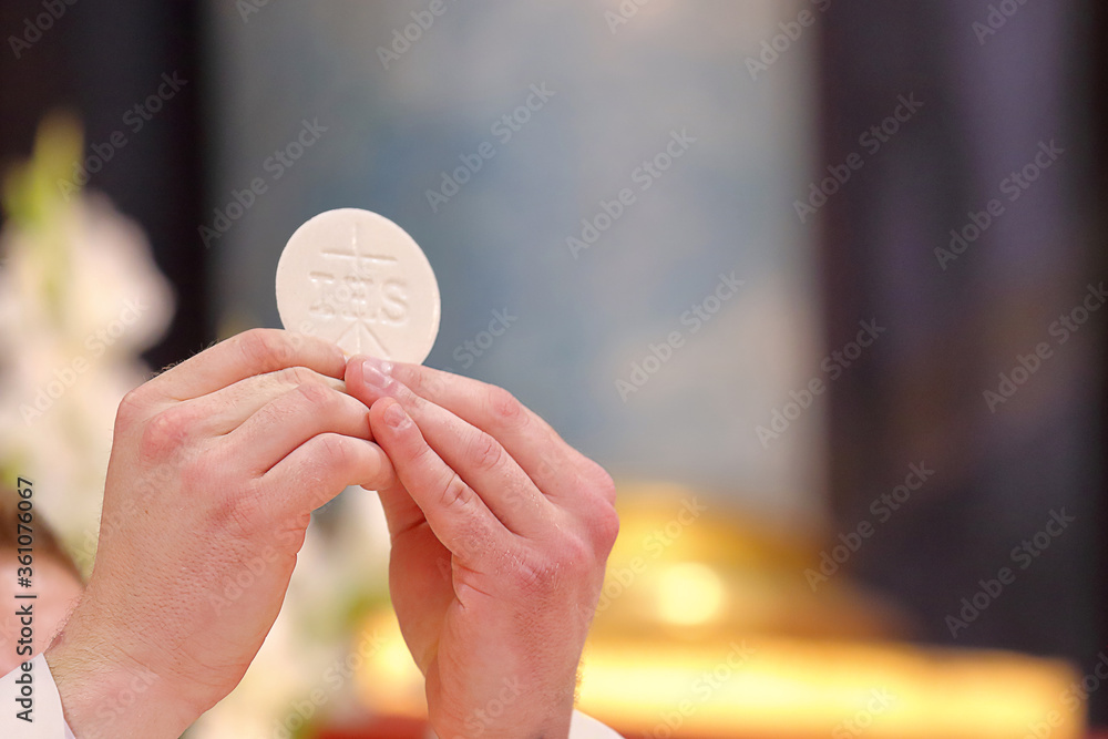 Holy host in the hands of the priest on the altar during the celebration of the mass - obrazy, fototapety, plakaty 