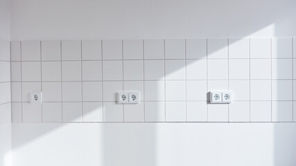 White wall with tiles and outlet in empty kitchen