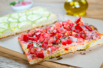 Pizza with tomato, ham, pesto and zucchini