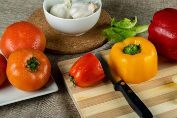 Sticker - Closeup shot of colorful peppers on a wooden cutting board tomatoes and garlic in the bowl