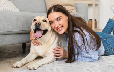 Wall Mural - Young happy woman with dog lying on floor