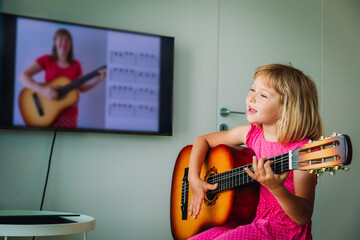 little girl having guitar lesson online at home