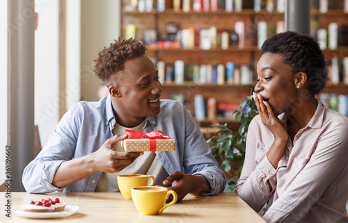 Fotografía Caring boyfriend surprising his girlfriend with unexpected gift at coffee shop