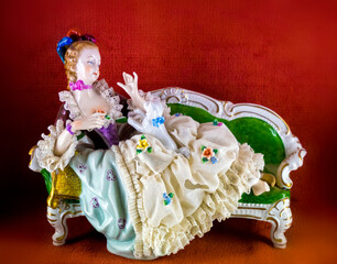 Medieval porcelain doll on vintage sofa
