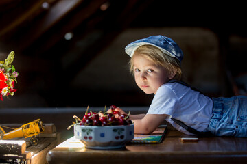 Poster - Cute beautiful child, blond kid, reading book and playing with construction blocks in a cozy attic room