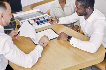 Wall Mural - black clients sign a contract while sitting at table with salesman, professional worker of dealership explain terms of the contract and show where to sign