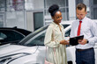 © alfa27 - good-looking dark-skinned woman have conversation with salesman in dealership, professional sales agent in formal shirt enjoy working with clients. woman want to buy a car