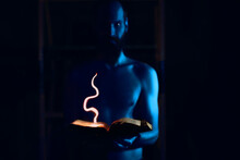 Man Wizard With Blue Skin Holds Burning Spell Book In His Hands
