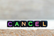Black bead with color letter in word cancel on wood background