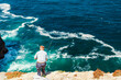 © eunikas - Elderly man fishing with a rod on high cliffs of Sao Vicente Cape, Portugal