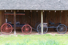 Two Beautiful Vintage Horse Cart Trap Vehicle Next To A Rustic Barn Stable Building