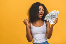 Happy Winner. Portrait Of African American Successful Woman 20s With Afro Hairstyle Holding Lots Of Money Dollar Banknotes Isolated Over Yellow Background.