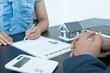 © Orathai - A real estate agent with a home model is talking to clients about renting a house and buying home insurance and contracting the contract after the formal negotiation is completed