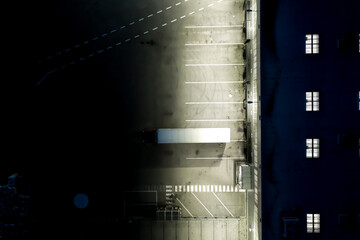 Night Aerial view of trucks unloading in logostics center. Logistics center in industrial city zone from above. Aerial view of trucks loading at logistic center