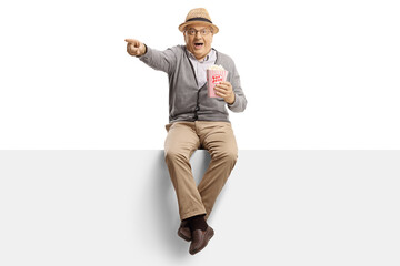 Poster - Elderly man sitting on a panel with popcorn and pointing