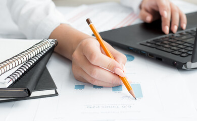 Business documents on office table with graph business diagram and woman working in the background with laptop