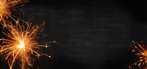 Wall Mural - silvester background banner panorama long- sparklers on a black board. top view with space for text