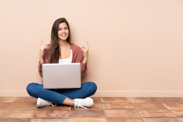 teenager student girl sitting on the floor with a laptop pointing up a great idea