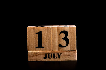 wooden calendar 13 July word on black background with copy space , selective focus at the calendar