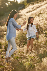 happy mother and little daughter on background of beautiful nature in sunset. summer time