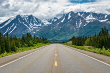 Road Winding Through The Alaskan Wilderness In Summer Surrounded By Mountains