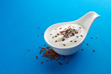 Wall Mural - Yogurt with flax seeds isolated on blue background